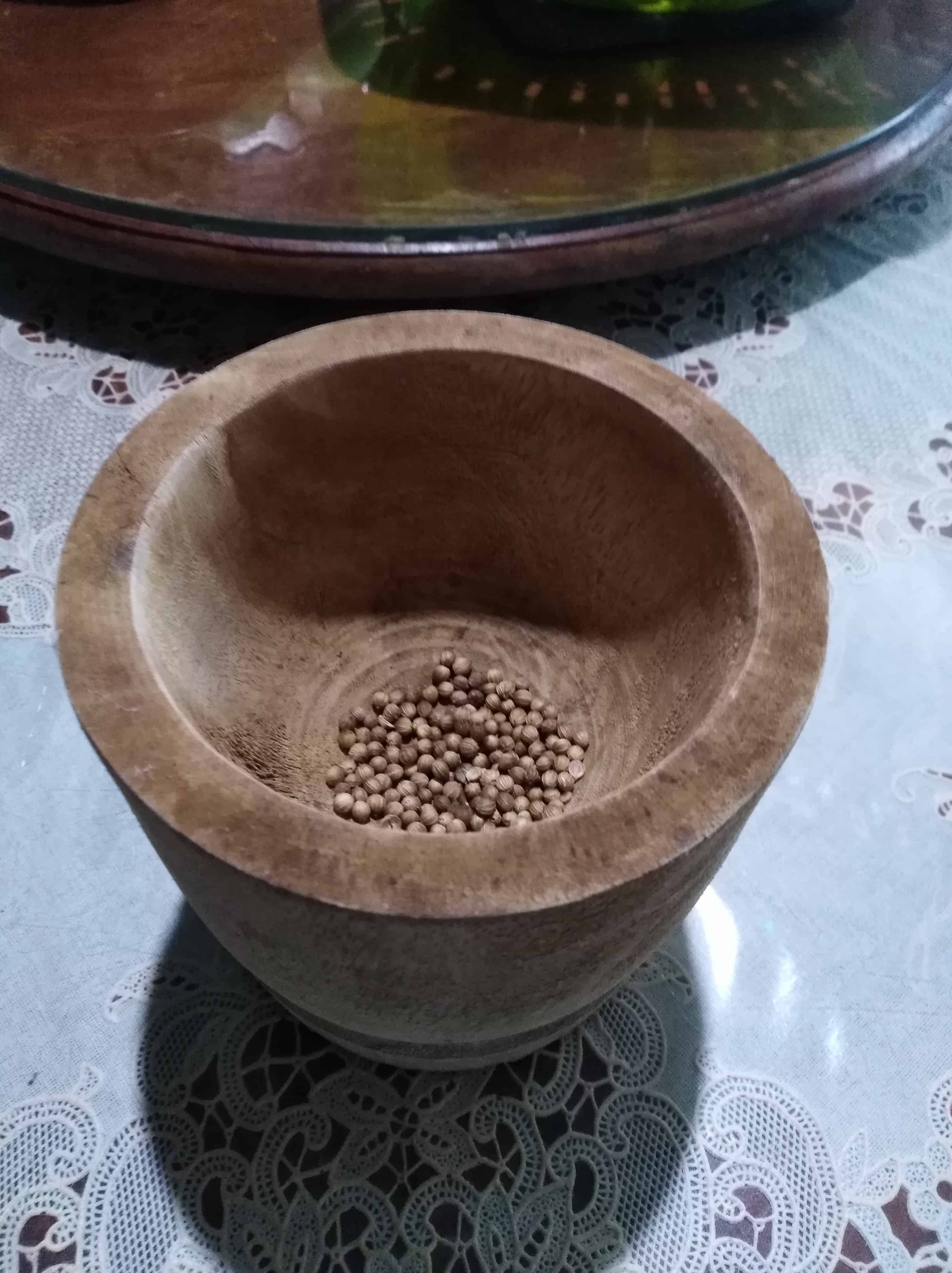 Whole coriander seeds in a mortar
